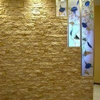 искусственный камень скалистый вместеcте с витражом украшают радиусную стену гостиной 