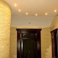 Круглая стена в холле частного дома оформлена декоративным камнем скалистый цвета слоновой кости