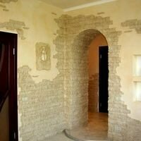 арочный проем в гостиной квартиры красиво оформлен диким камнем скалистый, цвет которого хорошо сочетается с цветом стен и напольного кафеля