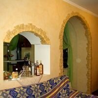 искусственный камень скалистый песочного цвета использован в отделке арок в гостиной частного дома