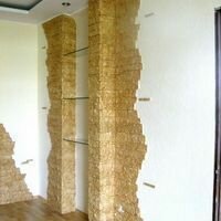 колонны, украшенные декоративным камнем скалистый, держат стеклянные полки в гостиной